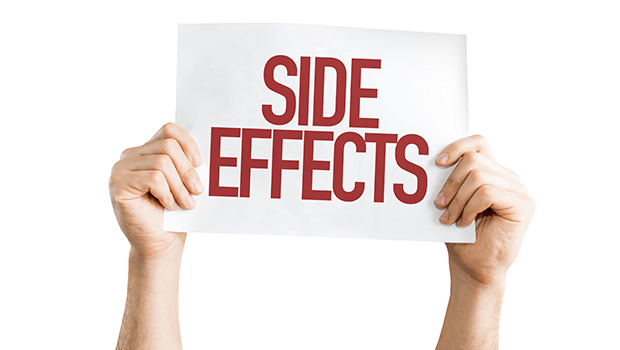 Two hands are holding up a white sign with the words "SIDE EFFECTS" written in bold red capital letters. The background is plain white.